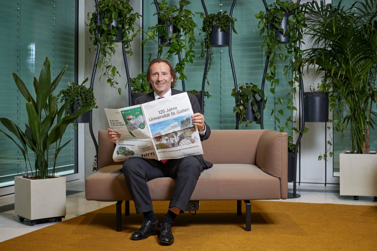 Christian Abegglen mit einer Zeitung zum 125-jährigen Bestehen der Universität St. Gallen