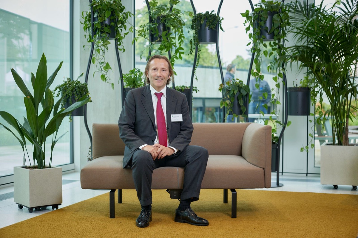 Christian Abegglen auf einem Sofa in einem hellen Raum mit Pflanzen